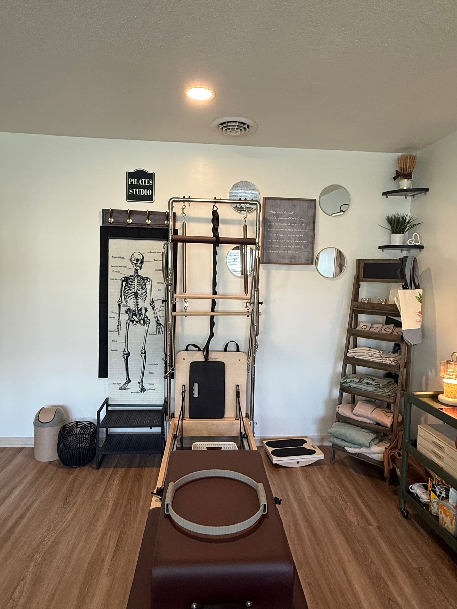 A Pilates reformer and tower beside the anatomy chart at the Rooted in Strength Pilates studio in Seaford, DE