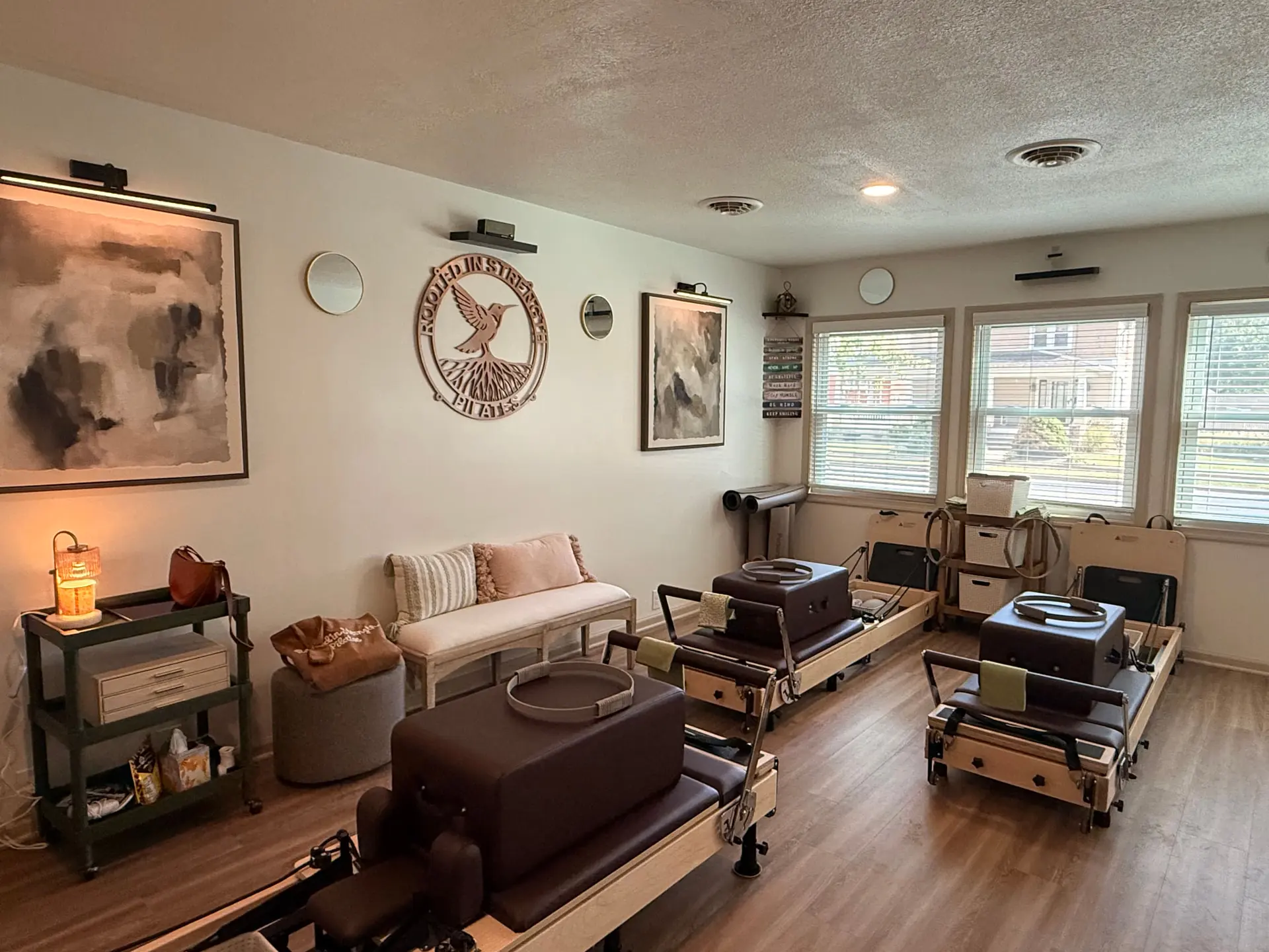 Inside the Rooted in Strength studio: Reformers, a cozy lounge seat and the hummingbird logo on the wall